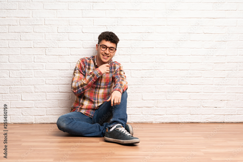 Young man sitting on the floor with glasses and smiling Young man sitting on the floor with glasses and smiling