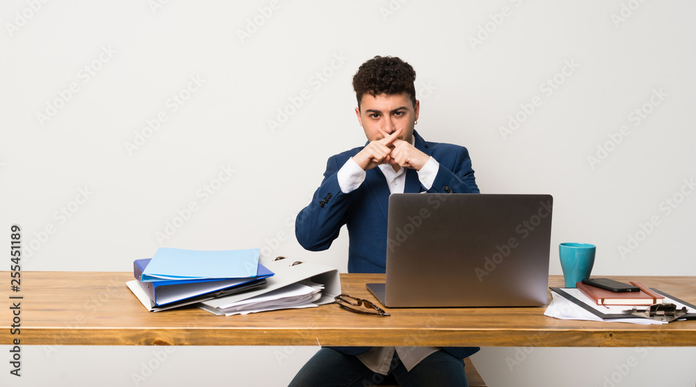 Business man in a office showing a sign of silence gesture Business man in a office showing a sign of silence gesture