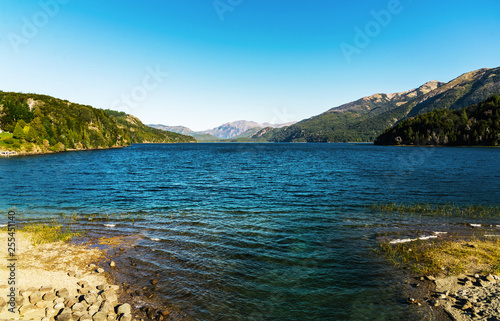 Colorful nature scenic photo of transparent aquamarine blue water surface of a lake with forest and Andes mountains in Patagonia  Argentina