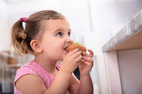 Girl Taking A Bite Of Cupcake In The Kitchen