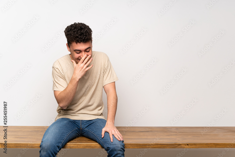 Young man sitting on table smiling a lot