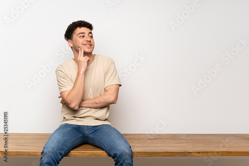 Young man sitting on table thinking an idea while looking up