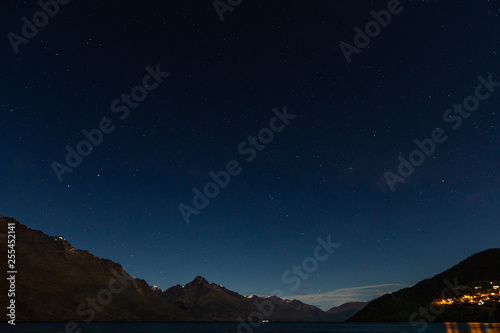 peaceful night sky full of stars above the lake and mountain range