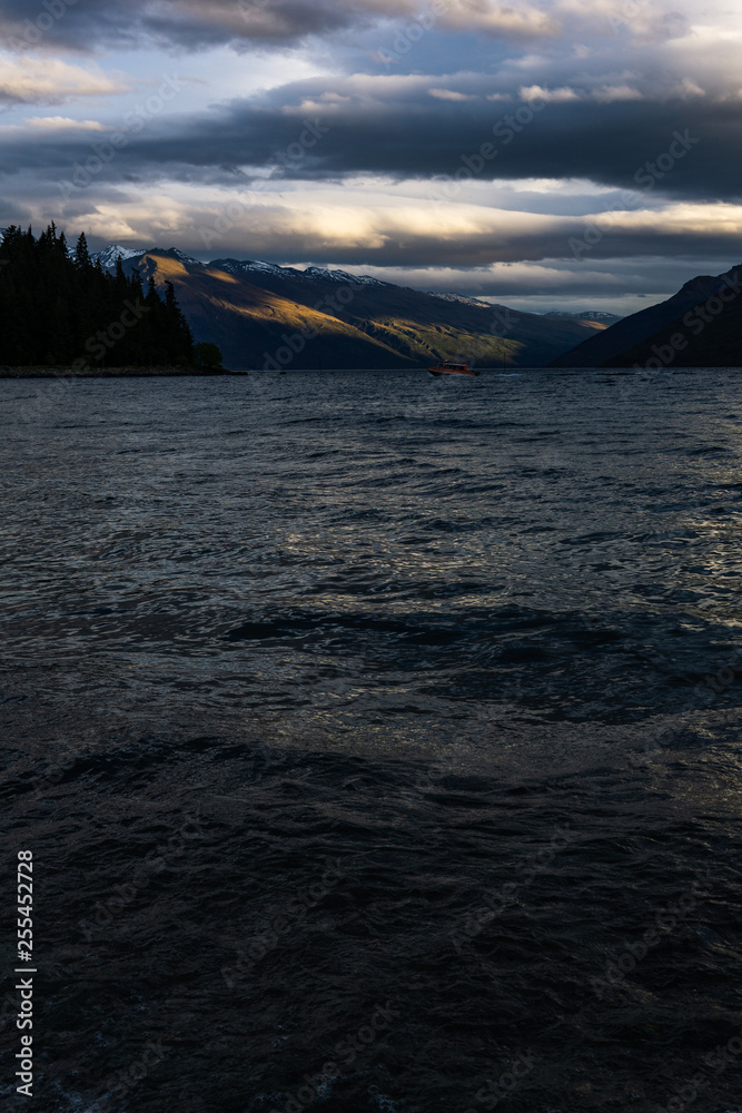 peaceful landscape during sunset with dramatic sky above the lake and mountain range