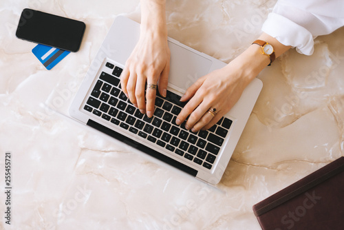 Handsome young woman typing at laptop keyboard. Work place concept, top view