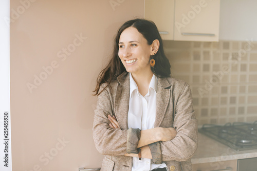 Attractive young woman smiling and looking away with crossed hnads in  her kitchen at home photo