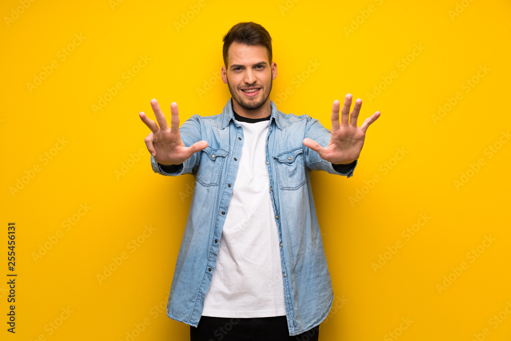 Handsome man over yellow wall counting nine with fingers Handsome man over yellow wall counting nine with fingers