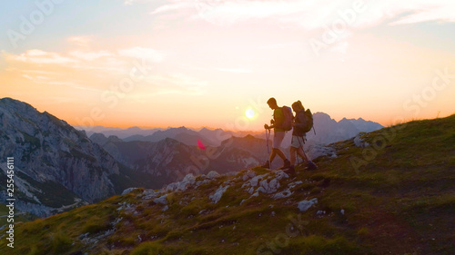 LENS FLARE: Active woman and boyfriend descending down the mountain at sunrise. © helivideo