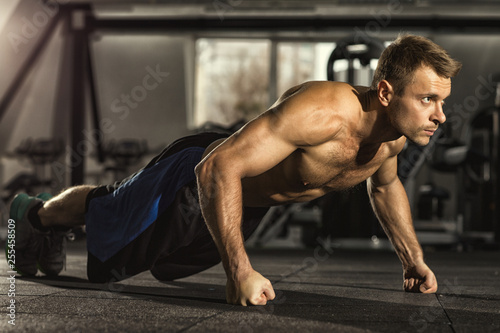 Pushing his limits. Full length shot of a shirtless man with toned muscular athletic body doing pushups working out at the gym confidence agility strength competition sports training concept