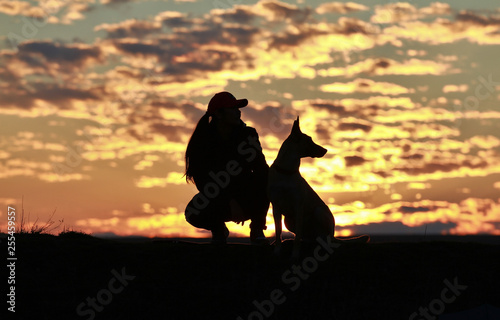 Silhouette of a girl and dogs against the backdrop of an incredible sunset  sky and clouds. Belgian Shepherd Malinois