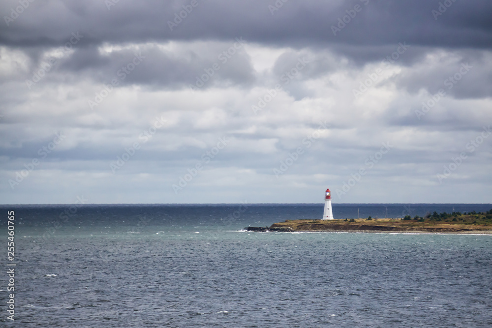 Lighthouse on the ocean coast during a cloudy day. Taken in New Victoria, Nova Scotia, Canada.
