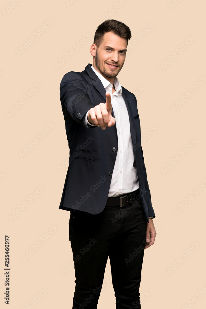 Handsome business man showing and lifting a finger over ocher background Handsome business man showing and lifting a finger over ocher background