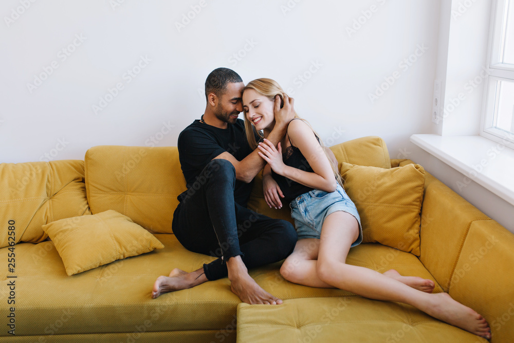 Lovers in a home clothes tenderly hugging with eyes closed on the couch. Romantic hug, happy faces, sensuality, tenderness, love.