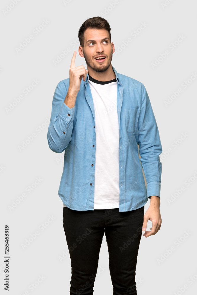Fototapeta premium Handsome man intending to realizes the solution while lifting a finger up over grey background