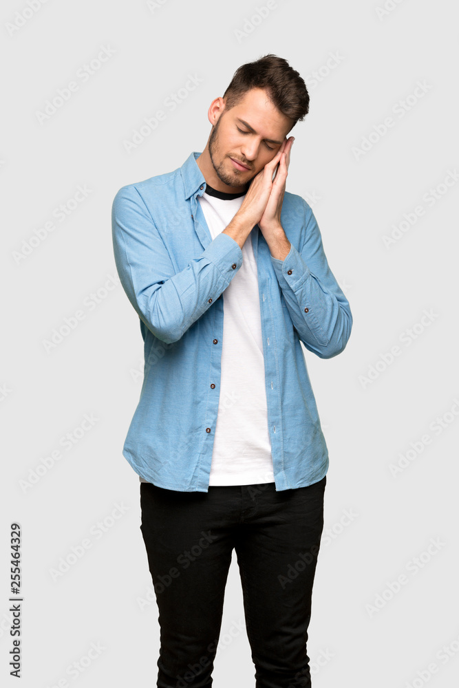 Handsome man making sleep gesture in dorable expression over grey background Handsome man making sleep gesture in dorable expression over grey background