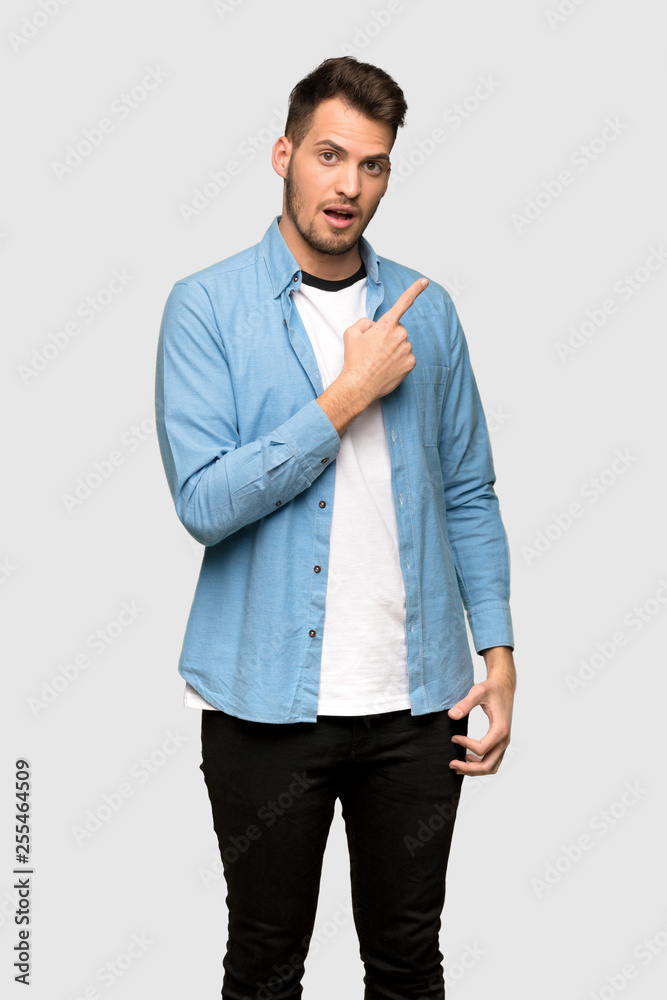 Handsome man surprised and pointing side over grey background Handsome man surprised and pointing side over grey background