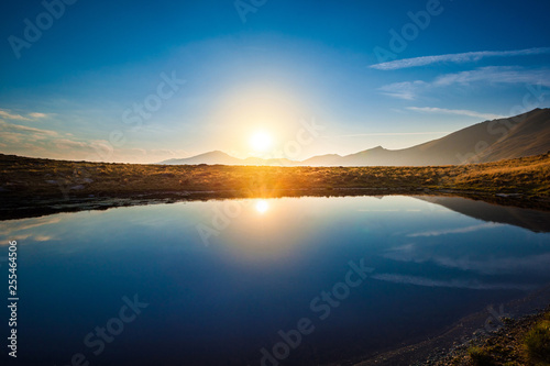 Fototapeta Naklejka Na Ścianę i Meble -  Mountain lake landscape at sunset with sun reflection scenic view