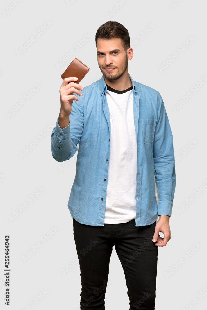 Handsome man holding a wallet over grey background Handsome man holding a wallet over grey background