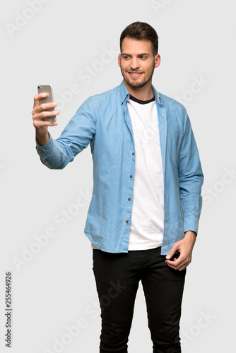 Handsome man making a selfie over grey background