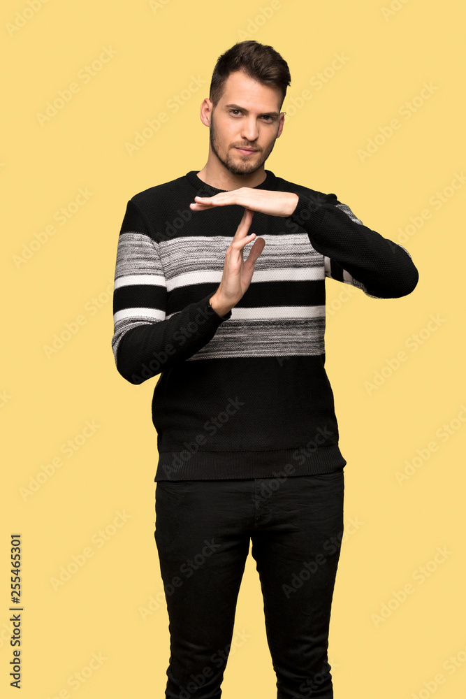 Handsome man making time out gesture over yellow background Handsome man making time out gesture over yellow background