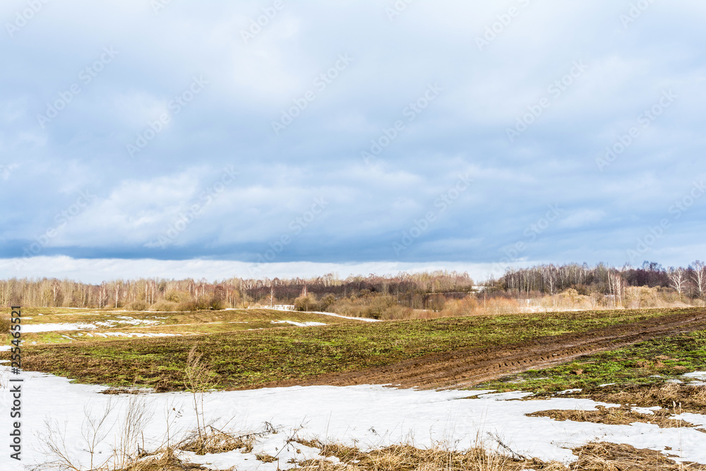 The melting of the snow on the fields in early spring, sunny day with blue sky and clouds The melting of the snow on the fields in early spring, sunny day with blue sky and clouds