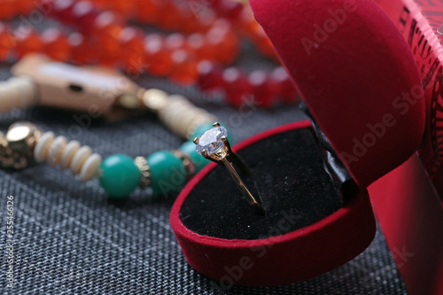 White gold diamond ring on top of colored stones. Romantic background ( Valentine's Day) 
