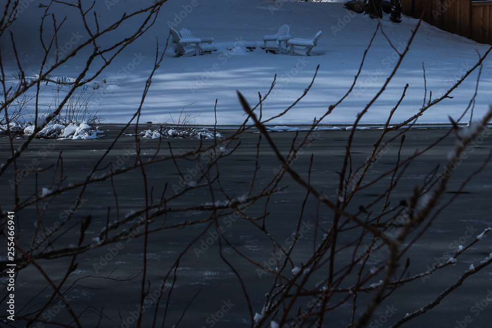 Fototapeta premium snow covered patio set near a lake