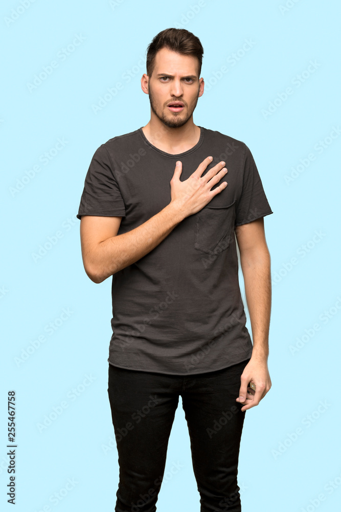 Man with black shirt surprised and shocked while looking right over blue background Man with black shirt surprised and shocked while looking right over blue background