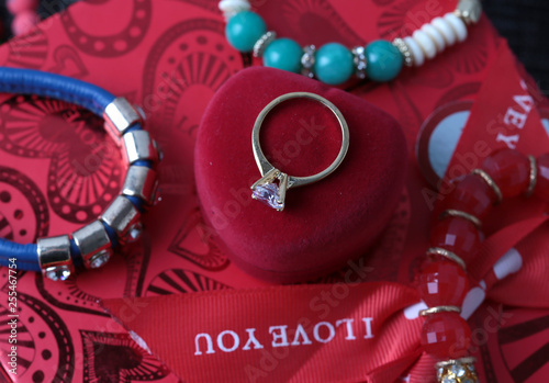 White gold diamond ring on top of colored stones. Romantic background ( Valentine's Day) 