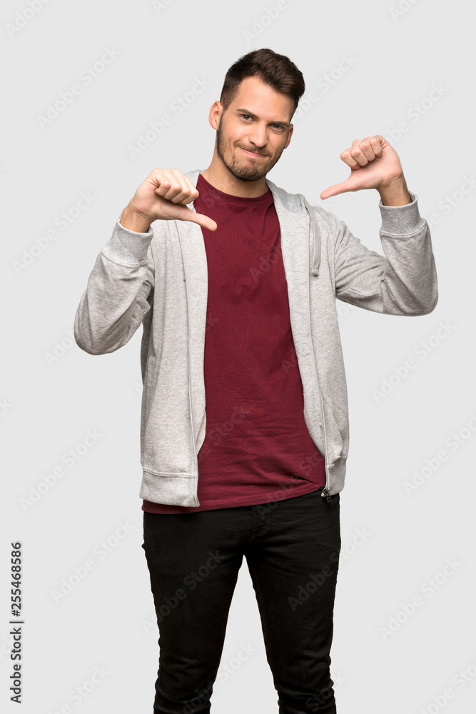 Man with sweatshirt showing thumb down over grey background Man with sweatshirt showing thumb down over grey background