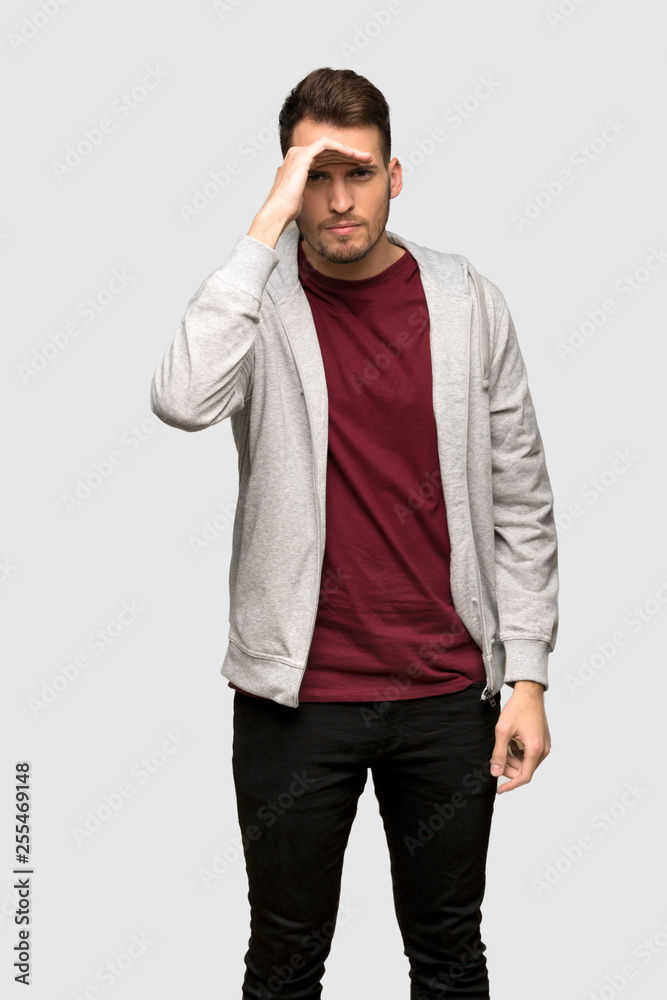 Man with sweatshirt looking far away with hand to look something over grey background Man with sweatshirt looking far away with hand to look something over grey background