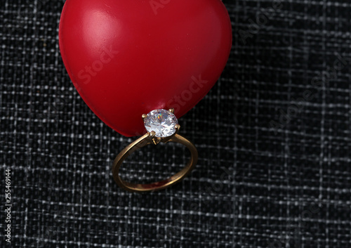 White gold diamond ring on top of colored stones. Romantic background ( Valentine's Day) 