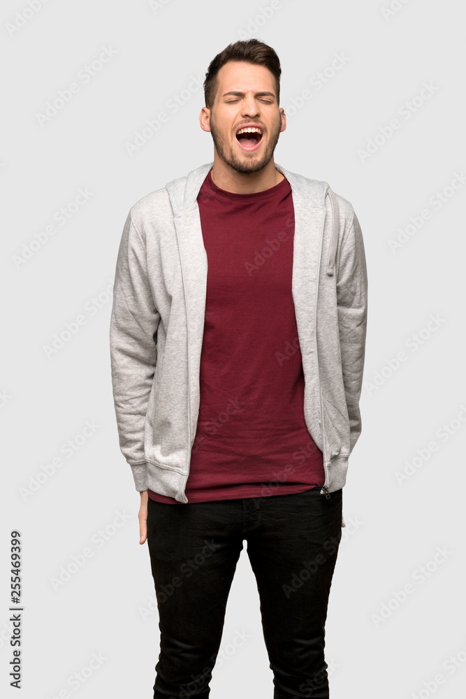 Fototapeta premium Man with sweatshirt shouting to the front with mouth wide open over grey background