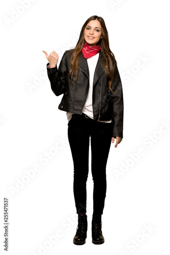 Full-length shot of Young woman with leather jacket pointing to the side to present a product on isolated white background