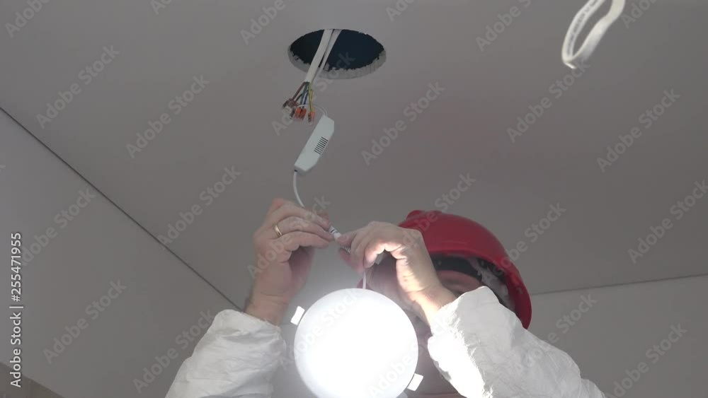 professional male worker install energy saving led light into ceiling hole