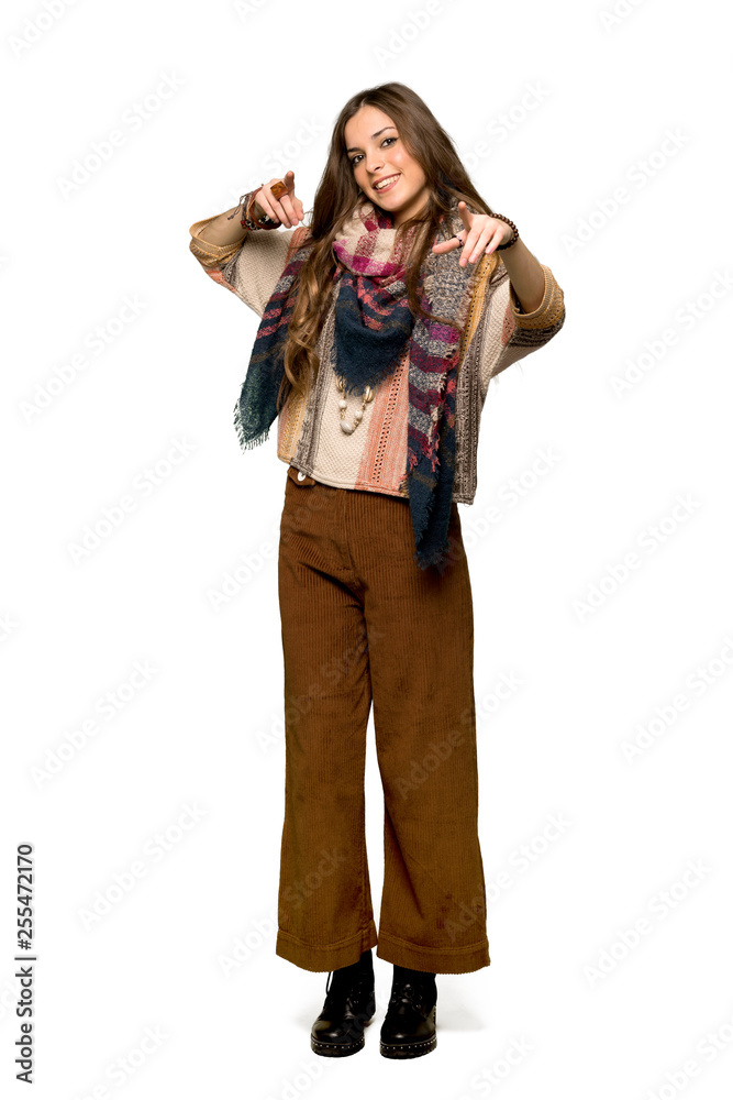 Full-length shot of Young hippie woman points finger at you while smiling on isolated white background