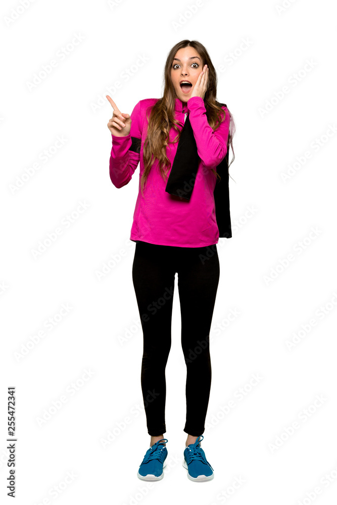Full-length shot of Young sport woman pointing up and surprised over isolated white background Full-length shot of Young sport woman pointing up and surprised over isolated white background