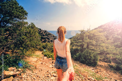 Follow me. Girl holds and leads her boyfriend by the hand in the mountains photo