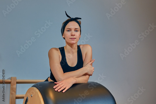 Beautiful girl - trainer in sports short top and sports leggings smiling is standing at the simulator for body stretching. Healthy lifestyle concept. Copy space photo