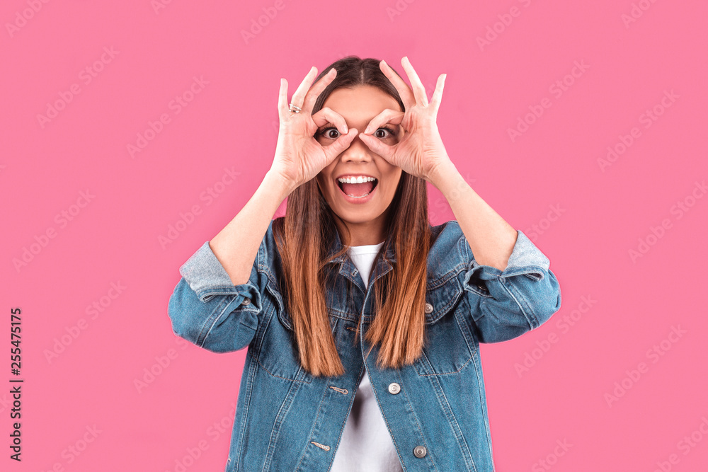 a young girl made her hands glasses on her eyes on a pink background a young girl made her hands glasses on her eyes on a pink background