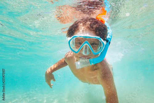 Happy kid boy snorkeling in clear blue sea