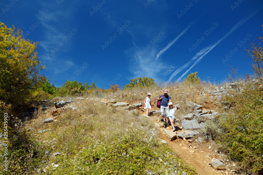 Father and two kids having fun hiking on warm and sunny summer day during family vacations in Zagoria, Greece