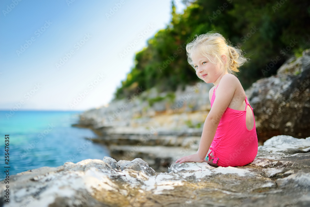 Cute little girl having fun at Emplisi Beach, picturesque stony beach in a secluded bay, with clear waters popular for snorkelling.