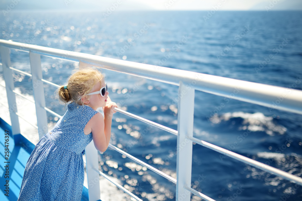 Adorable young girl enjoying ferry ride staring at the deep blue sea. Child having fun on summer family vacation in Greece. - obrazy, fototapety, plakaty 