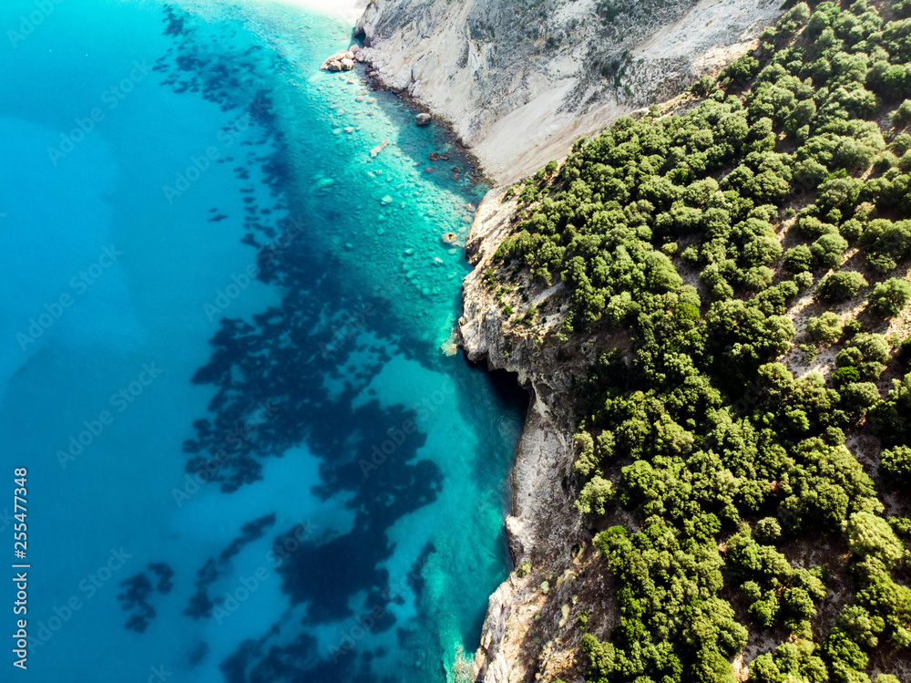 Scenic aerial top down view of picturesque jagged coastline of Kefalonia with clear turquoise waters, surrounded by steep cliffs.