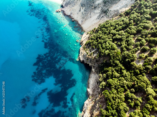 Scenic aerial top down view of picturesque jagged coastline of Kefalonia with clear turquoise waters, surrounded by steep cliffs. © MNStudio