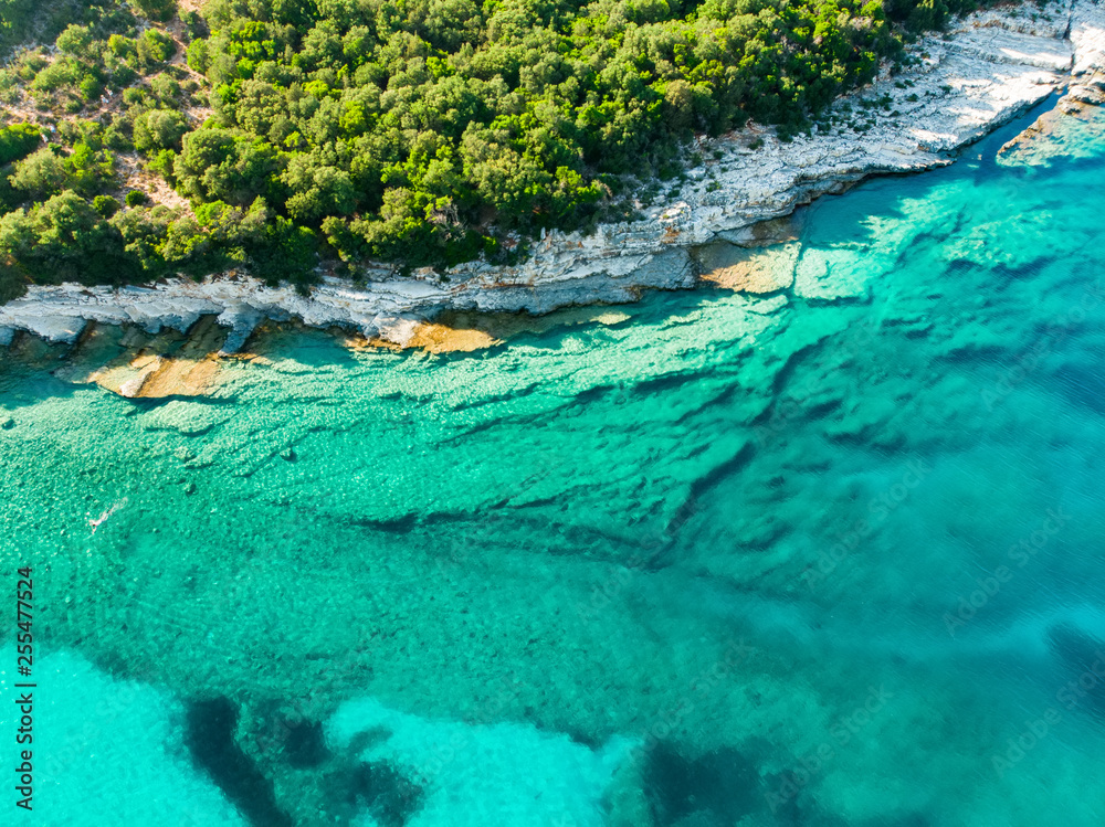 Aerial view of Emplisi Beach, picturesque stony beach in a secluded bay, with clear waters popular for snorkelling. Small pebble beach near Fiscardo town of Kefalonia, Greece. Aerial view of Emplisi Beach, picturesque stony beach in a secluded bay, with clear waters popular for snorkelling. Small pebble beach near Fiscardo town of Kefalonia, Greece.