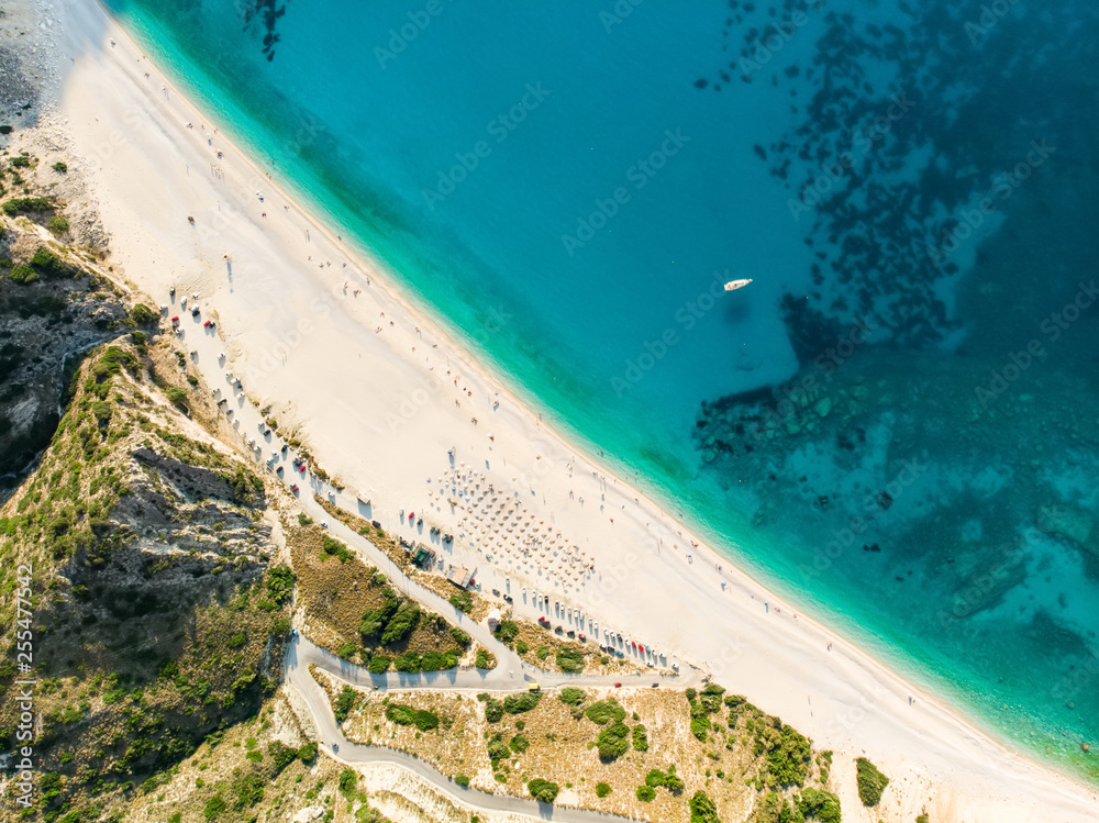 Aerial top down view of Myrtos beach, the most famous and beautiful beach of Kefalonia, a large coast with turqoise water and white coarse sand, surrounded by steep cliffs.