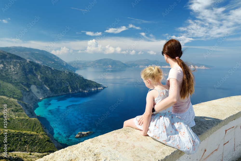 Mother and child enjoying the view of picturesque jagged coastline of Kefalonia with clear turquoise waters, surrounded by steep cliffs.