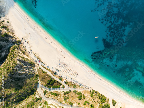 Aerial top down view of Myrtos beach, the most famous and beautiful beach of Kefalonia, a large coast with turqoise water and white coarse sand, surrounded by steep cliffs. © MNStudio
